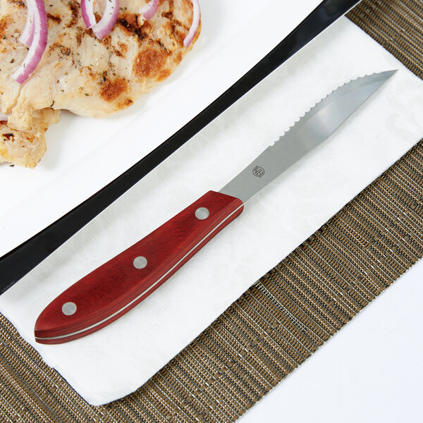An American Metalcraft stainless steel steak knife on a plate of food.