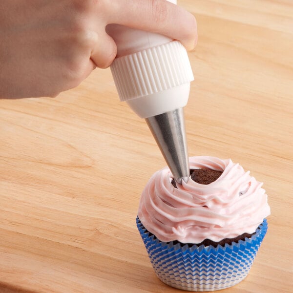 A hand using an Ateco closed star piping tip to frost a cupcake.