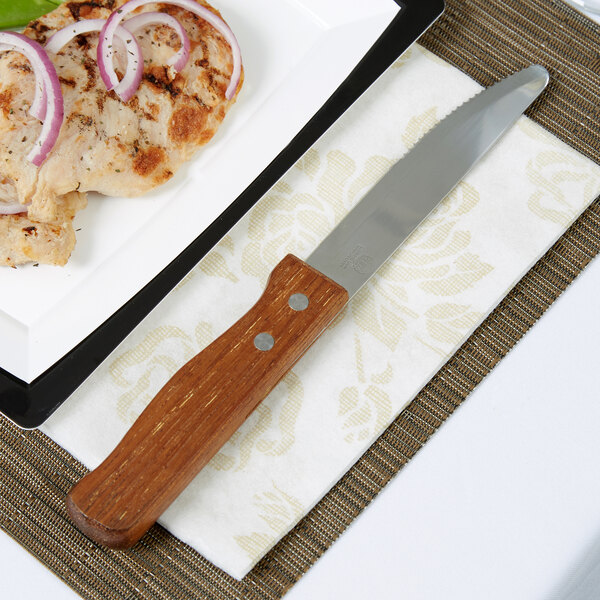An American Metalcraft stainless steel steak knife on a plate with food
