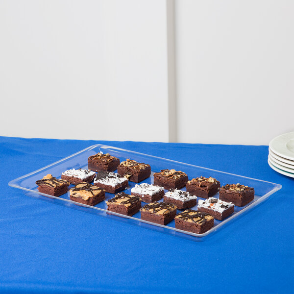 A Cal-Mil clear bakery tray of brownies on a blue table.