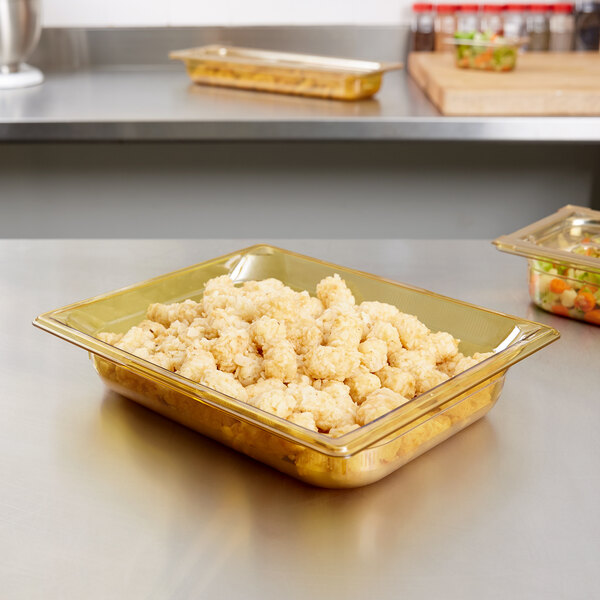 A Vollrath amber plastic food pan on a counter with food in it.