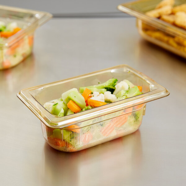 A Vollrath amber plastic food pan filled with vegetables on a salad bar counter.