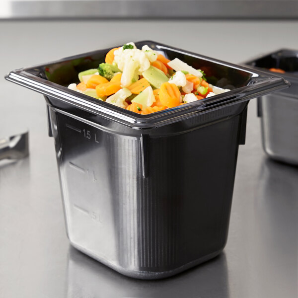 A Vollrath black plastic food pan with vegetables inside.