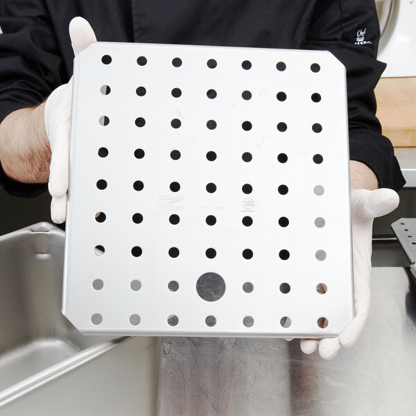 A person holding a metal tray with small holes in it.