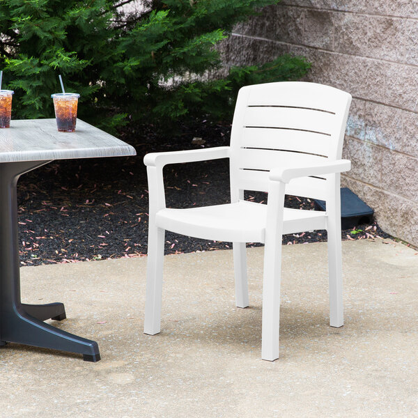A white Grosfillex Acadia resin armchair on a concrete patio.