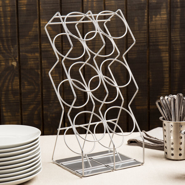 A Cal-Mil platinum metal wire rack with 6 cylinders holding flatware and plates.