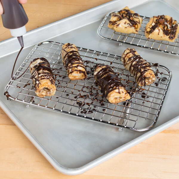 A Vollrath stainless steel wire pan grate with chocolate covered cookies on a tray.