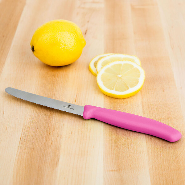 A Victorinox utility knife with a pink handle next to a lemon slice.