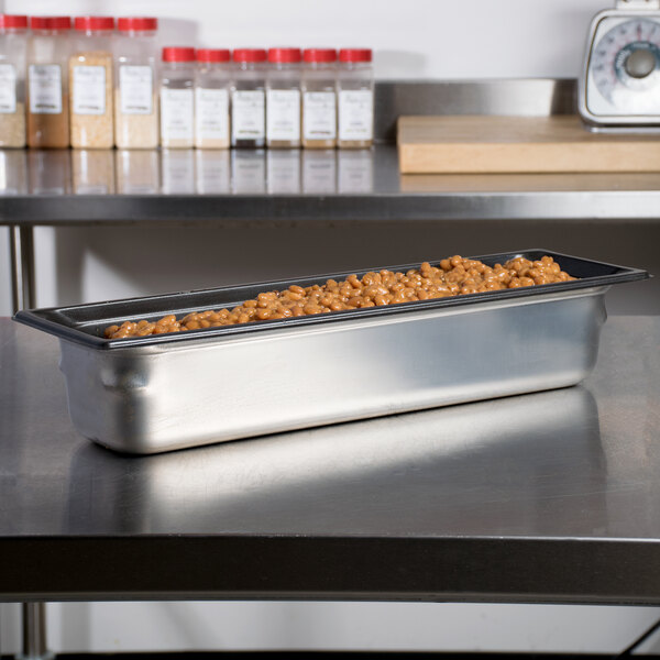 A Vollrath stainless steel steam table pan filled with food on a counter.