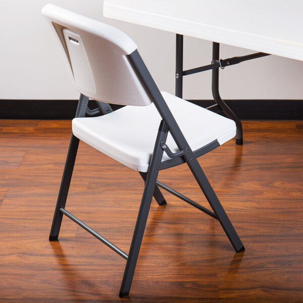 A white Lifetime contoured folding chair on a wooden surface.