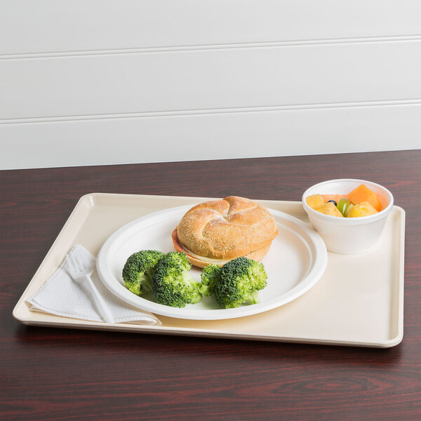 A white dietary tray with a sandwich, broccoli, and fruit on it.