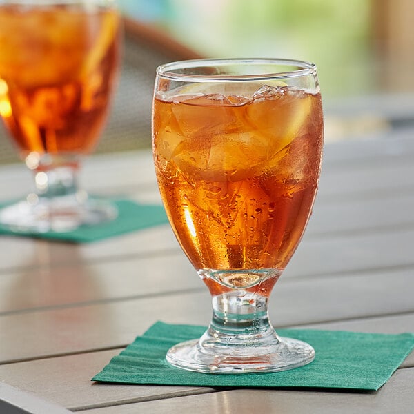 An Acopa customizable glass filled with iced tea on a table.