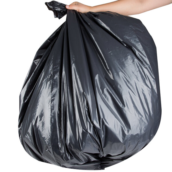A person holding a Berry low density black trash bag.
