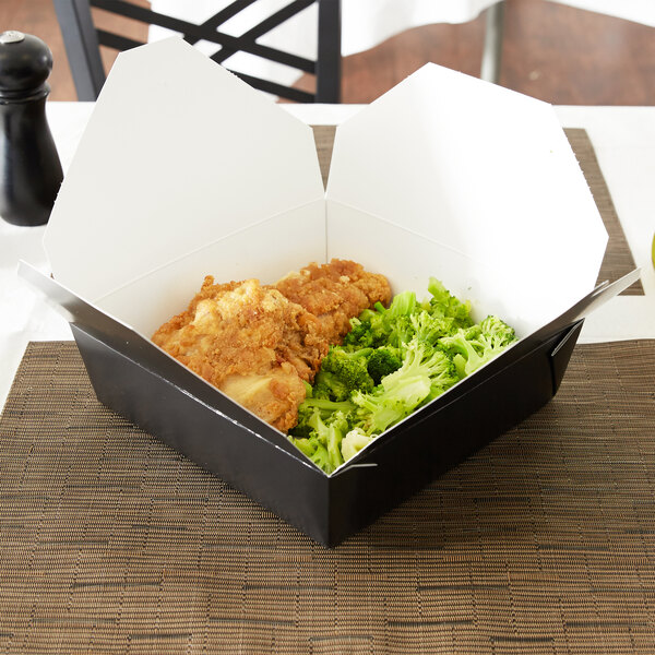 A black Fold-Pak Bio-Pak take-out box filled with food on a table.