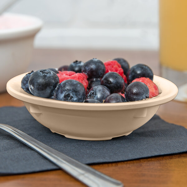 A tan GET SuperMel bowl filled with blueberries and raspberries on a table.