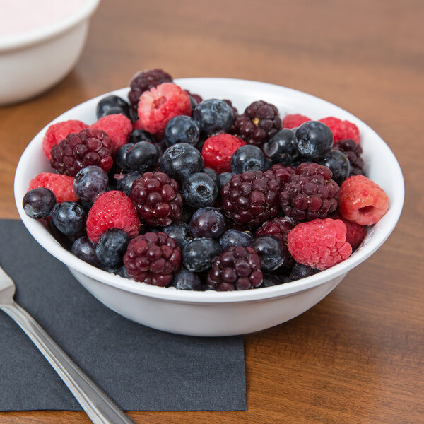 A white SuperMel bowl filled with berries on a table.