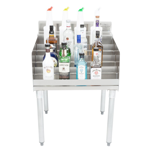 A silver Eagle Group underbar shelf with bottles of alcohol on it.