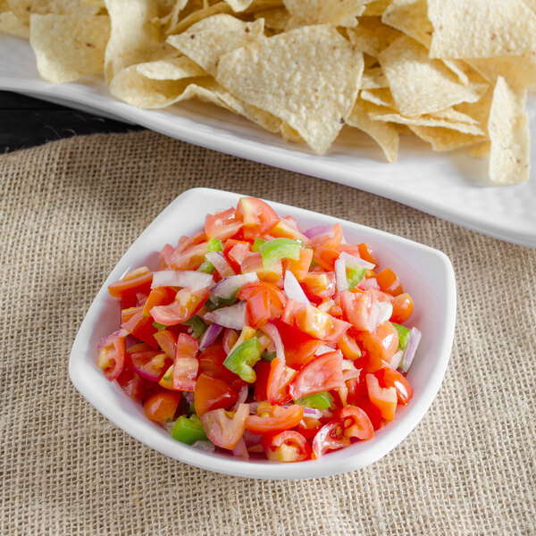 A white Carlisle melamine square bowl filled with salsa and tortilla chips.