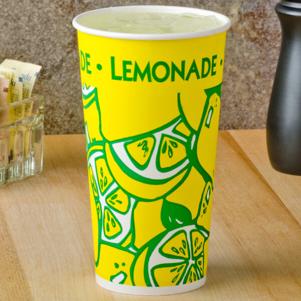 A yellow paper cup with lemons on it filled with lemonade.