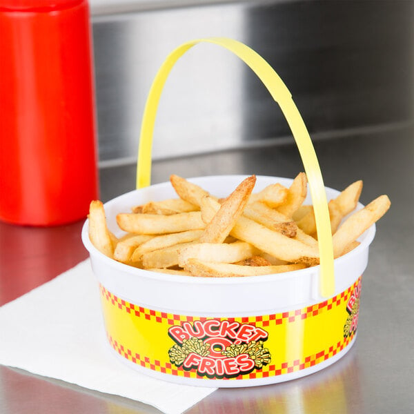 A red plastic French fry bucket filled with fries on a counter.