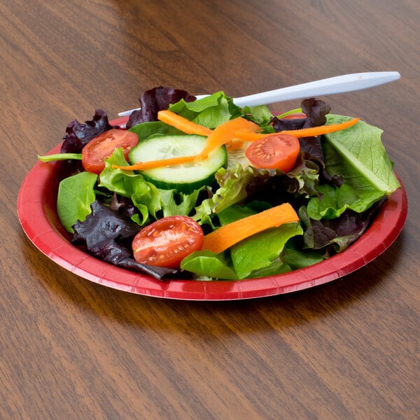 A Classic Red Creative Converting paper plate with salad on it.