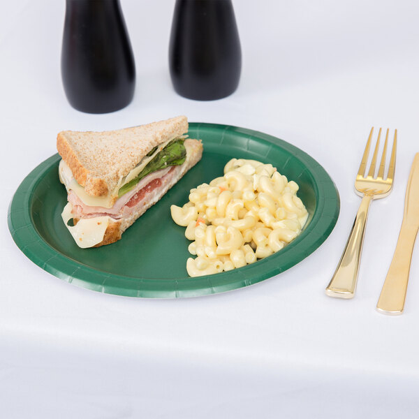 A Hunter Green Creative Converting paper plate with a sandwich and a drink.