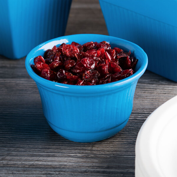 A Tablecraft sky blue cast aluminum bowl filled with cranberries.