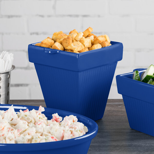 A Tablecraft cobalt blue cast aluminum square condiment bowl filled with food on a counter.