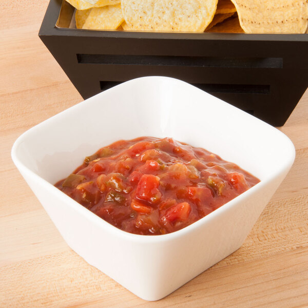 A bowl of salsa and chips in a white CAC porcelain bowl on a wood surface.
