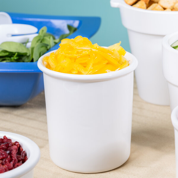 A white Tablecraft condiment bowl with yellow food inside on a table with bowls of food.