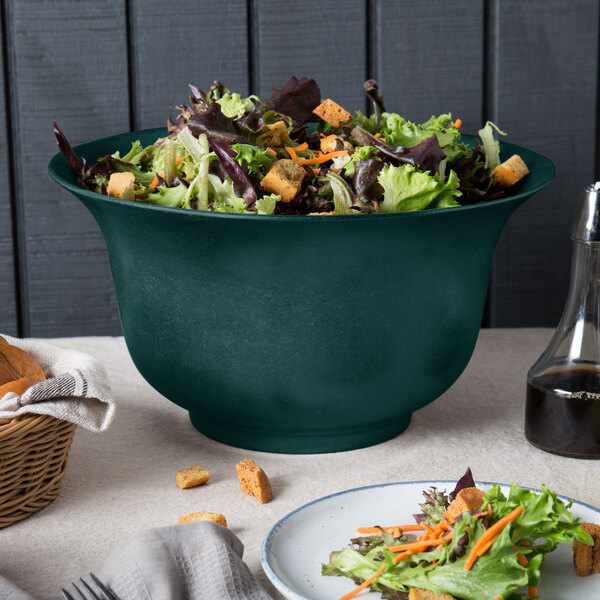 A Tablecraft hunter green cast aluminum tulip salad bowl filled with salad on a table.