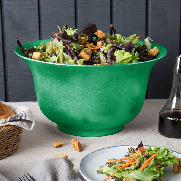 A green Tablecraft cast aluminum tulip salad bowl on a table with salad.