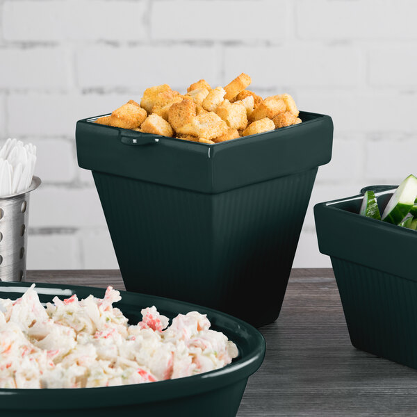 A group of Tablecraft hunter green cast aluminum square condiment bowls filled with food on a table.