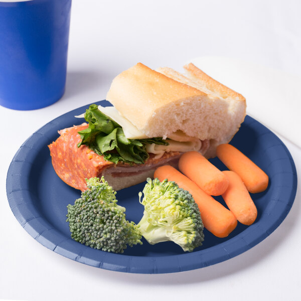 A Creative Converting navy blue paper plate with a sandwich and carrots on it.