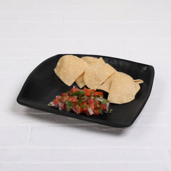 A black Elite Global Solutions Ore square plate with tortilla chips and salsa on it.