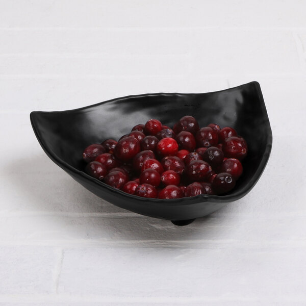 A black Elite Global Solutions triangle bowl filled with cherries.