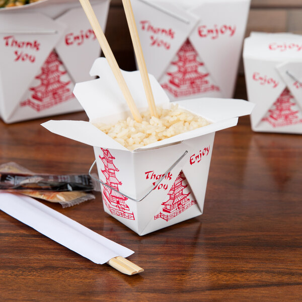 A white Fold-Pak Chinese take-out container of food with chopsticks on a table.