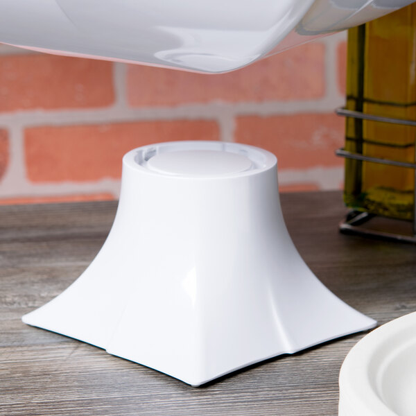 A white Carlisle melamine pedestal with a bowl on top on a wood surface.