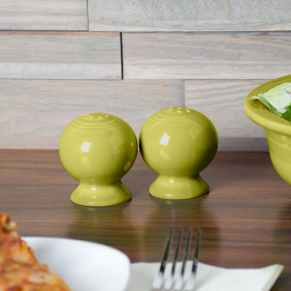 A wood table with yellow Fiesta salt and pepper shakers.