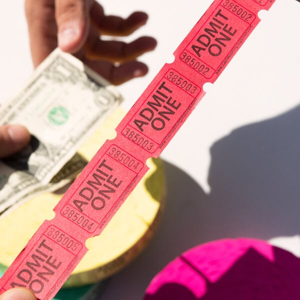 A hand holding a red strip of Carnival King "Admit One" tickets.