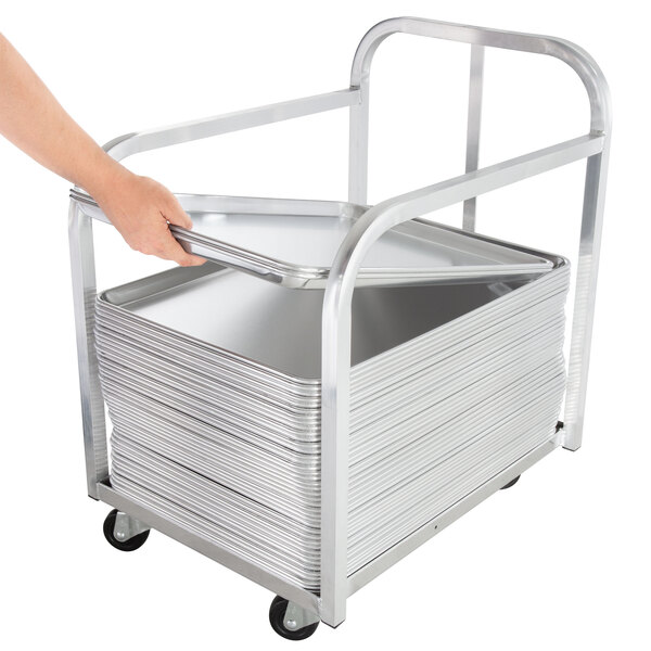 A hand using the handle on an Advance Tabco bun pan transport truck to move a tray.