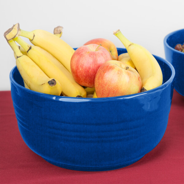 A Tablecraft cobalt blue cast aluminum fruit bowl filled with bananas and apples.