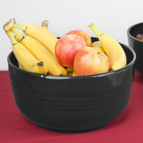 A Tablecraft natural cast aluminum bowl filled with bananas and red apples on a table.