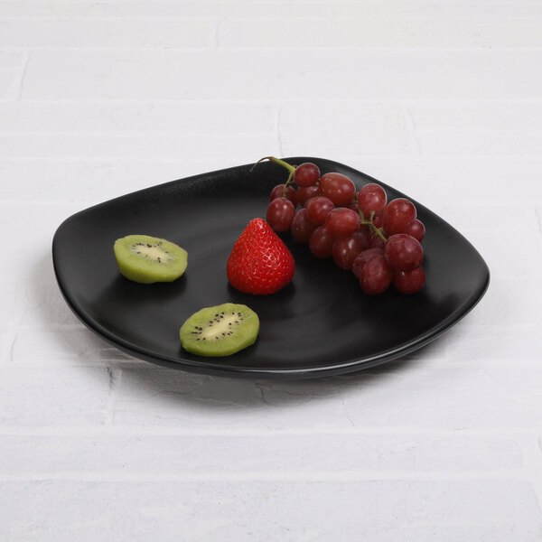 A black Elite Global Solutions square melamine plate with kiwi and other fruit on it.