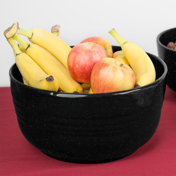 A Tablecraft Midnight with Blue Speckle cast aluminum fruit bowl filled with bananas and apples on a table.