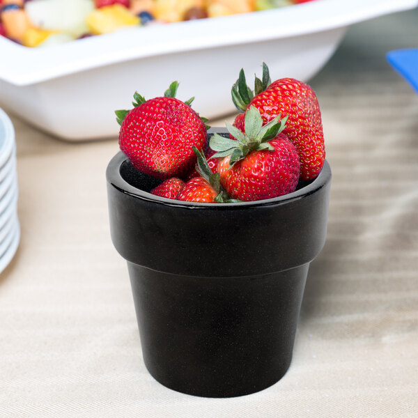 A Tablecraft black cast aluminum condiment bowl with strawberries inside.