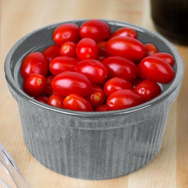 A Tablecraft granite souffle bowl filled with cherry tomatoes on a wooden table.