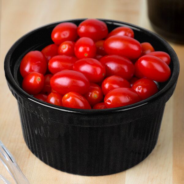 A Tablecraft Midnight with Blue Speckle cast aluminum bowl of cherry tomatoes on a counter.