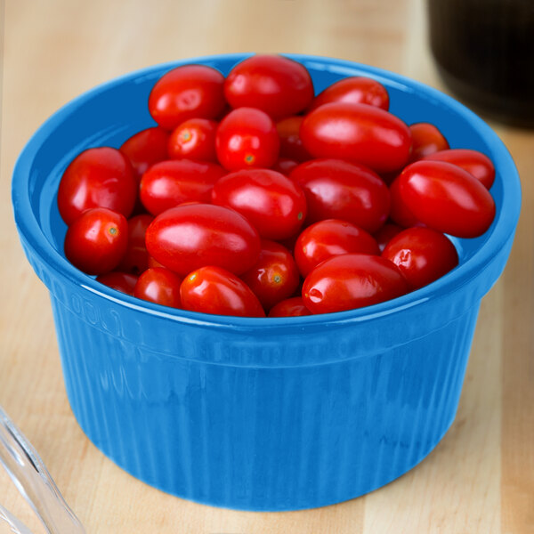 A blue Tablecraft cast aluminum souffle bowl filled with cherry tomatoes.