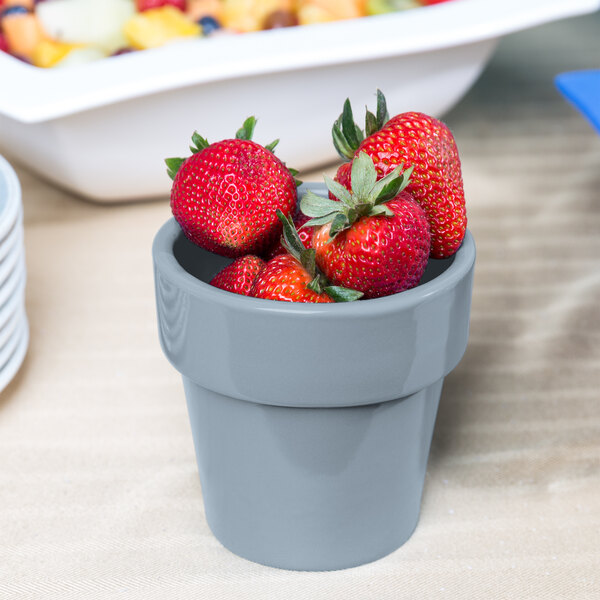 A Tablecraft gray cast aluminum round condiment bowl filled with strawberries on a table.